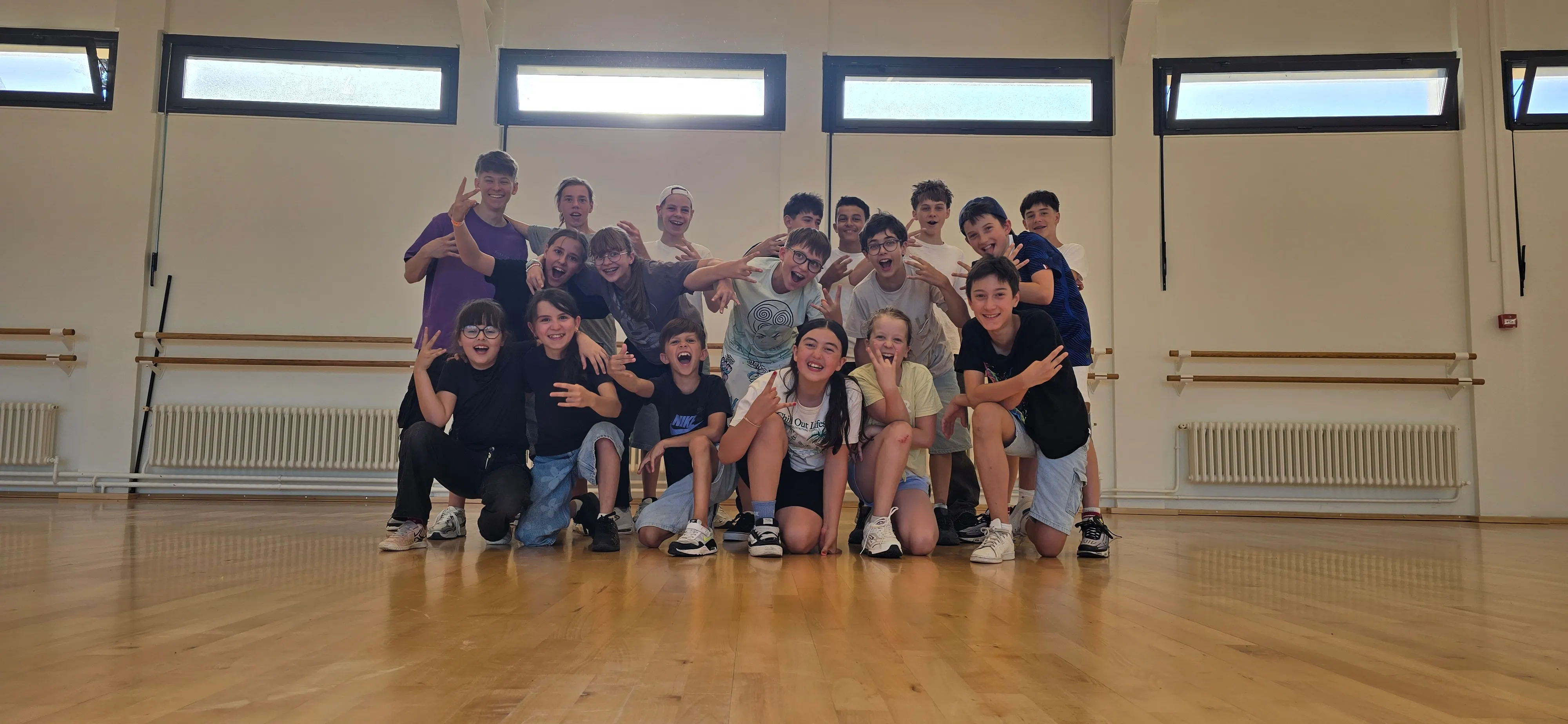 Groupe de jeunes danseurs HDMI Team réunis dans une salle d'entraînement, parquet au sol et grandes fenêtres en arrière-plan