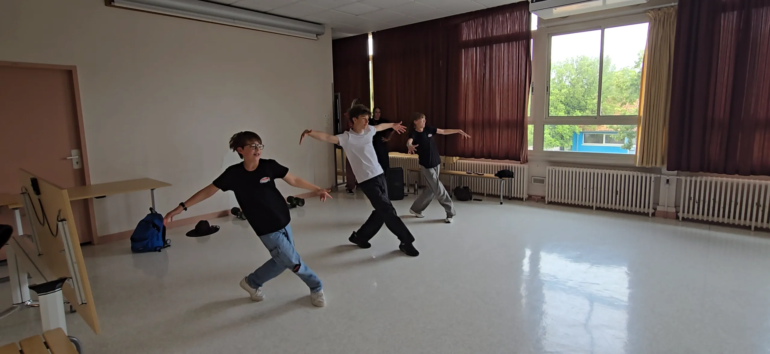 Un encadrant HDMI Team et un élève exécutent le même mouvement, bras écartés, lors d'une intervention en école primaire
