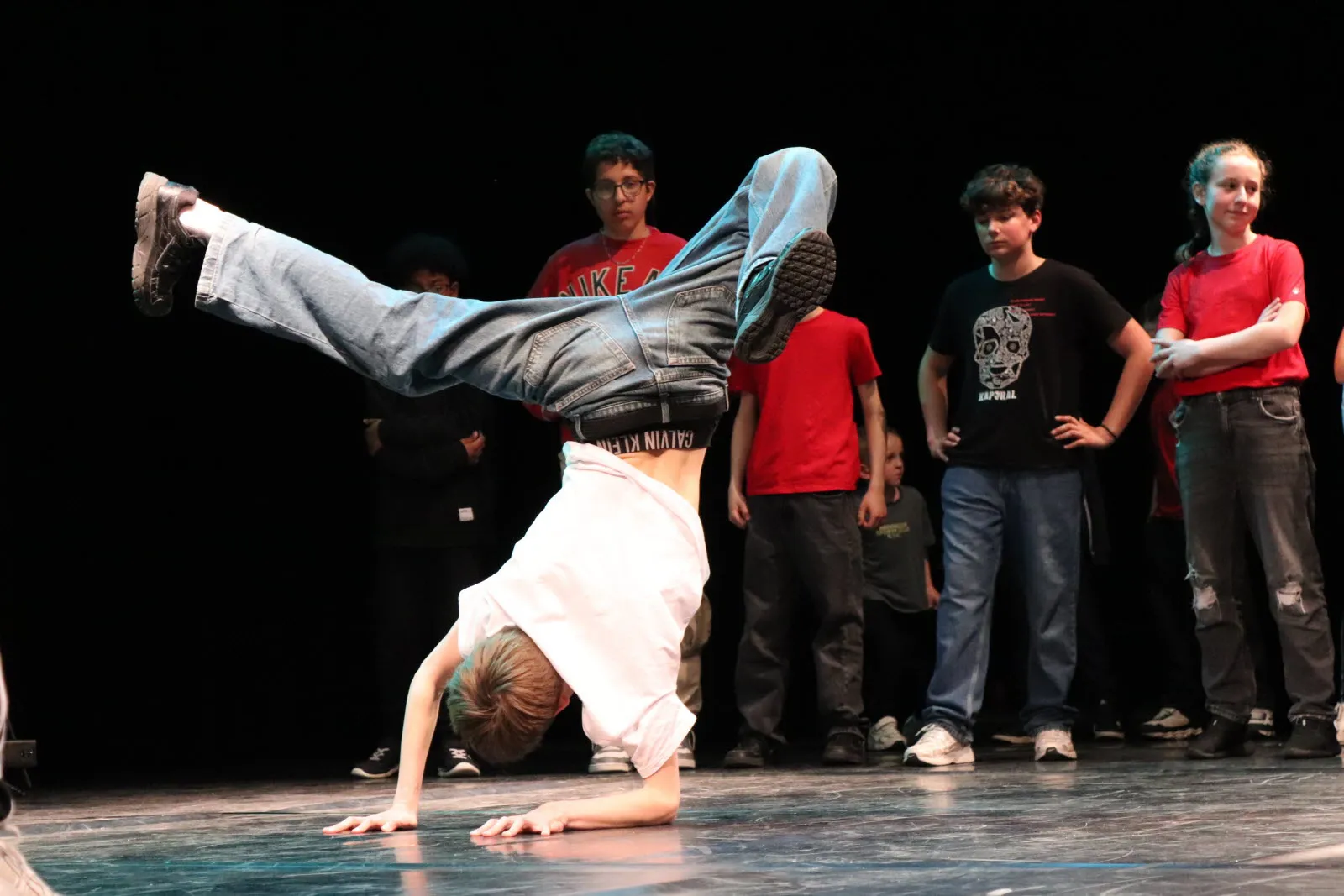 Un jeune danseur HDMI Team présente une figure de breaking sur scène, entouré du groupe — photo Catherine Bonnet